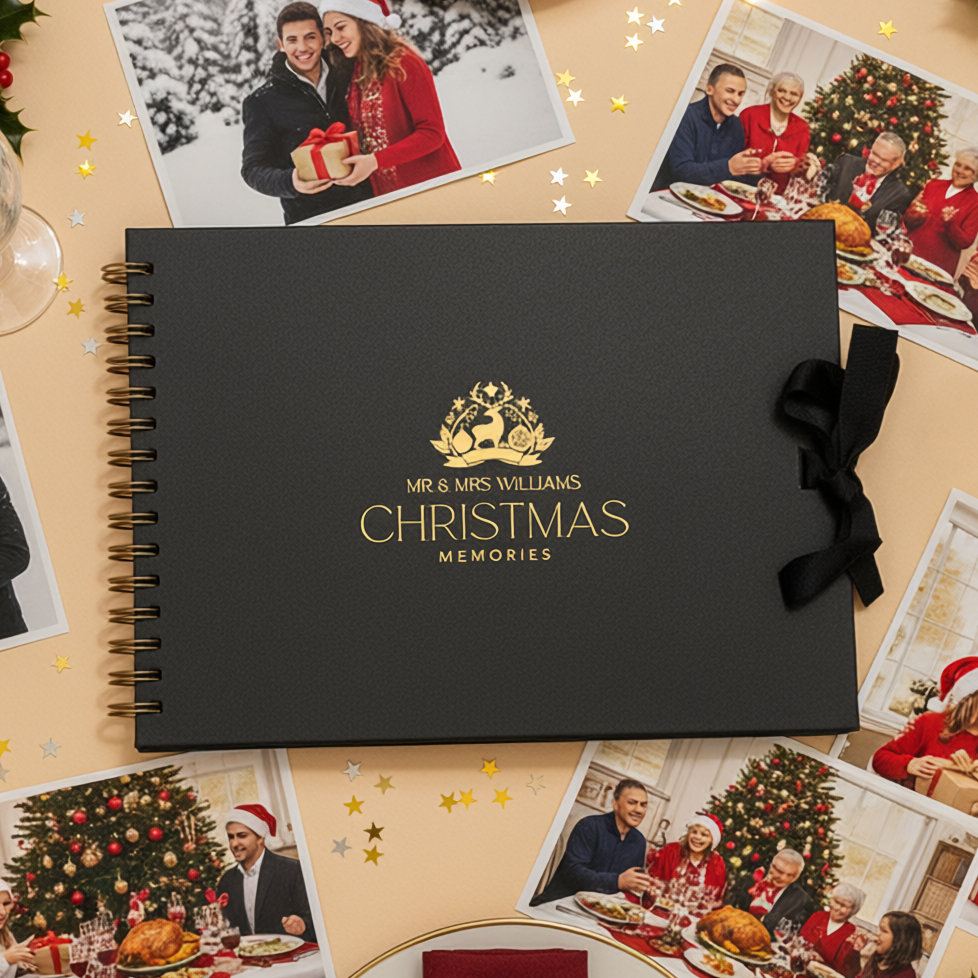 Black 'Mr & Mrs Williams Christmas Memories' album surrounded by Christmas-themed photos and decorations on a festive table.